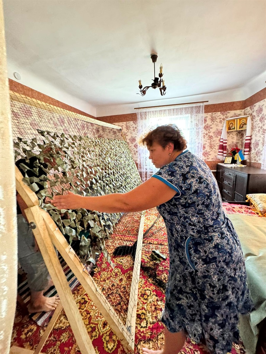 Пані Віра показує рухливу стійку для плетіння сіток в їхньому будинку